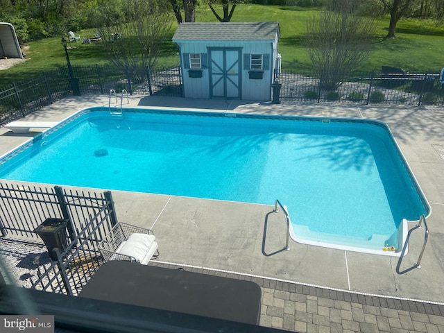 view of swimming pool with a fenced in pool, fence, a shed, a yard, and an outbuilding