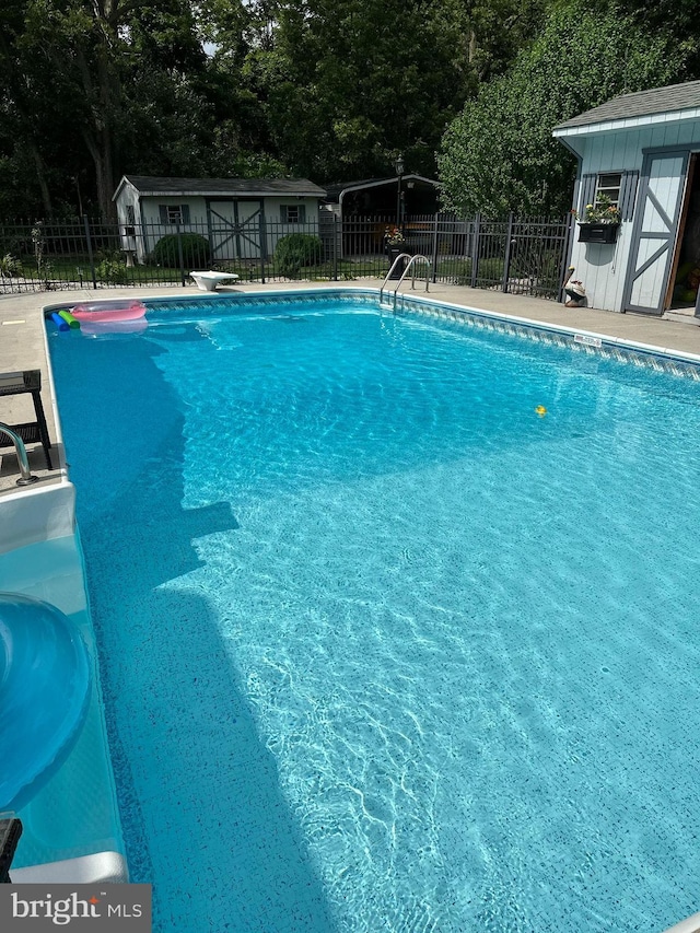 view of pool with a diving board, a fenced in pool, an outdoor structure, and fence