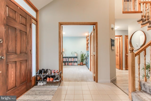 tiled foyer entrance with lofted ceiling and stairway