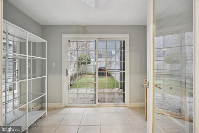 doorway with baseboards and tile patterned floors