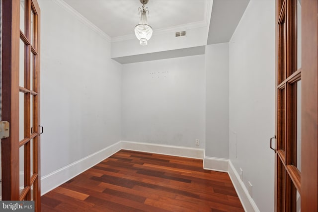 spare room featuring dark wood-type flooring, visible vents, crown molding, and baseboards