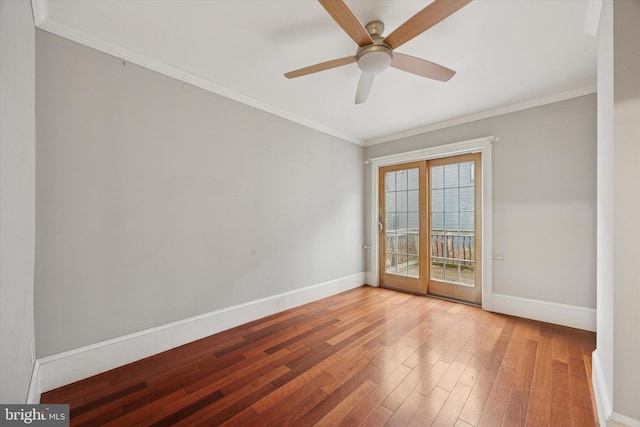 empty room with ornamental molding, wood finished floors, a ceiling fan, and baseboards