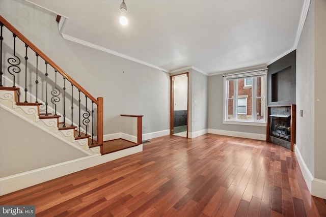 unfurnished living room featuring a fireplace, stairway, hardwood / wood-style floors, ornamental molding, and baseboards