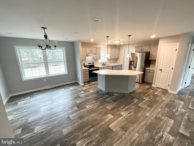 kitchen with baseboards, a kitchen island, a sink, light countertops, and appliances with stainless steel finishes