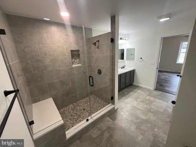 bathroom featuring vanity, baseboards, and a stall shower