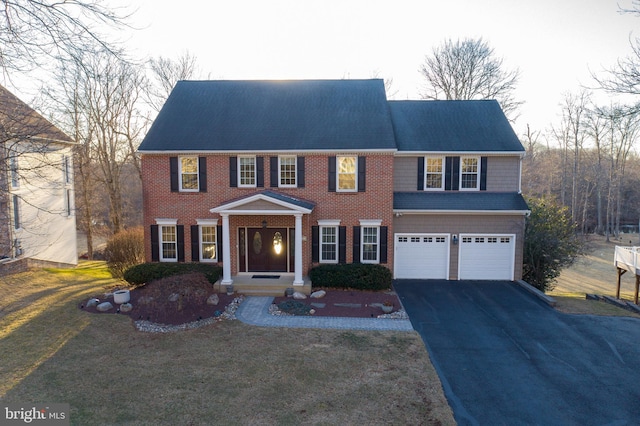 view of front of home with aphalt driveway, an attached garage, brick siding, and a front yard