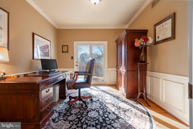 office space with wainscoting, light wood-style floors, visible vents, and ornamental molding