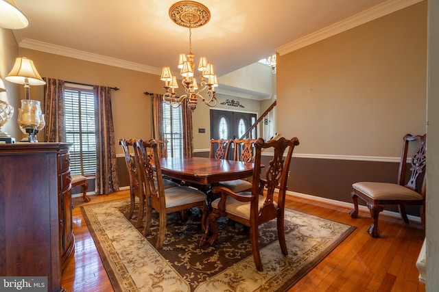 dining space with a chandelier, crown molding, baseboards, and wood-type flooring