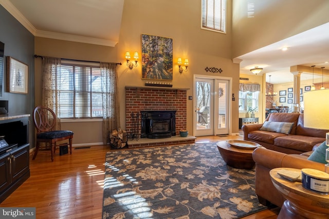 living room with visible vents, crown molding, baseboards, decorative columns, and hardwood / wood-style flooring