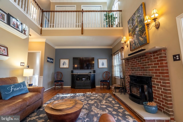 living area featuring baseboards, a high ceiling, wood finished floors, and ornamental molding