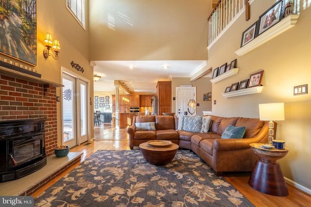 living area featuring french doors, baseboards, a towering ceiling, and wood finished floors