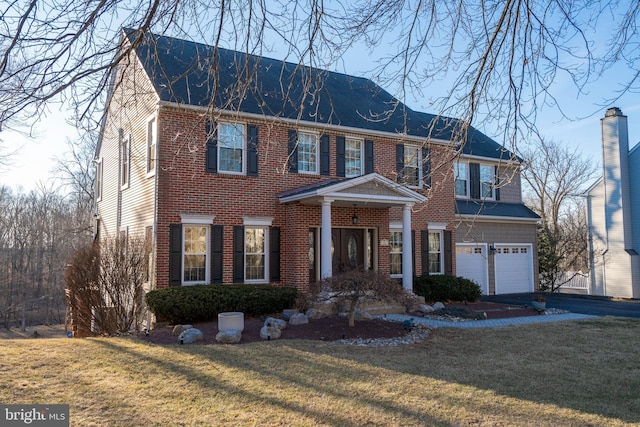 view of front facade with aphalt driveway, a front yard, a garage, and brick siding