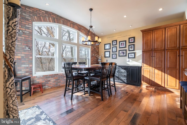 dining area with a notable chandelier, recessed lighting, brick wall, and light wood-style floors