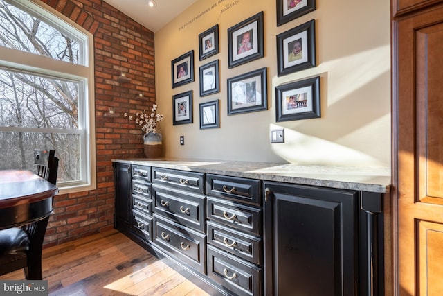 bar featuring wood finished floors and brick wall