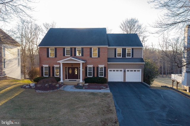 view of front of property with brick siding, driveway, a front lawn, and a garage