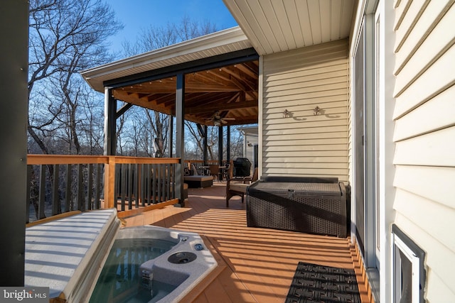 wooden terrace featuring hot tub deck surround and ceiling fan