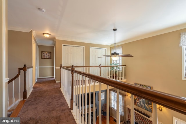 hallway featuring an upstairs landing, carpet flooring, crown molding, and baseboards