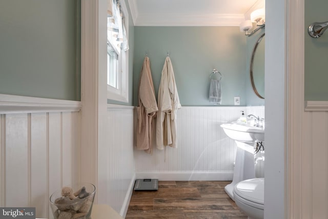 bathroom with toilet, ornamental molding, wood finished floors, and wainscoting