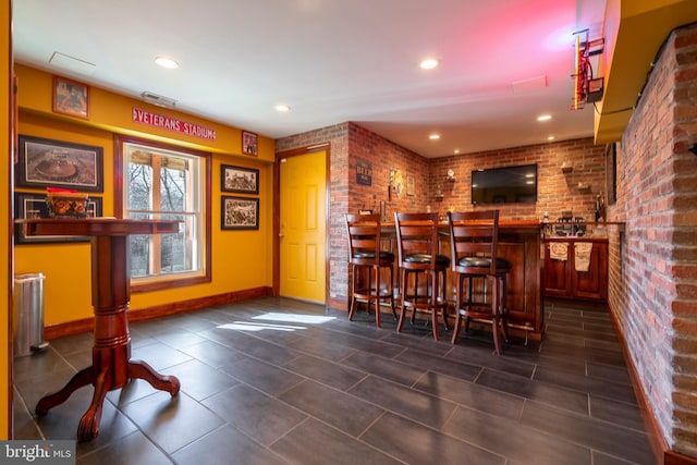 bar with wet bar, recessed lighting, baseboards, and brick wall