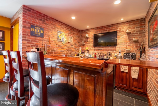 bar featuring wet bar, recessed lighting, and brick wall