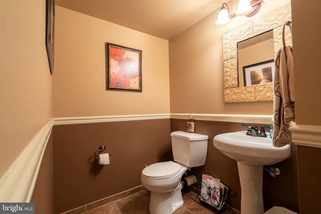 half bath with tile patterned floors, toilet, and baseboards