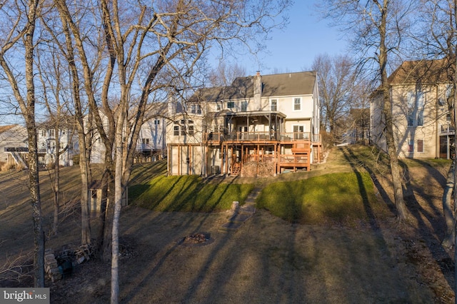 rear view of house with a yard, a chimney, a deck, and stairs