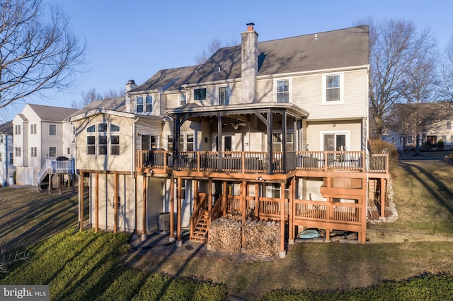 back of house featuring a deck, a lawn, and a chimney