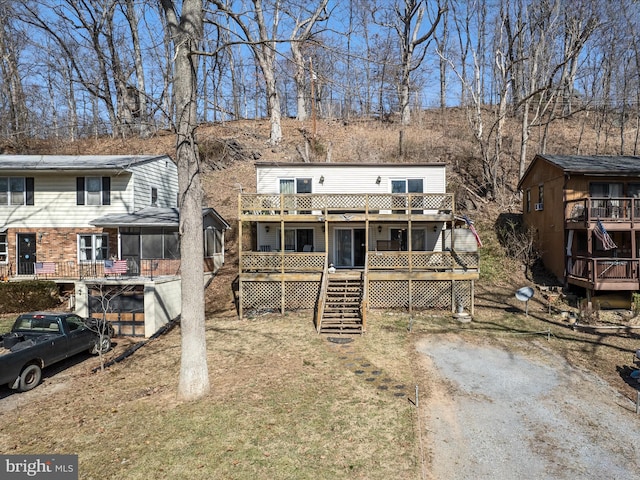 view of front of home with a wooden deck, stairway, and a sunroom