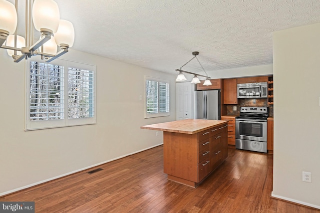 kitchen with visible vents, butcher block countertops, appliances with stainless steel finishes, and dark wood finished floors