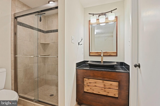 bathroom featuring a shower stall, toilet, and vanity