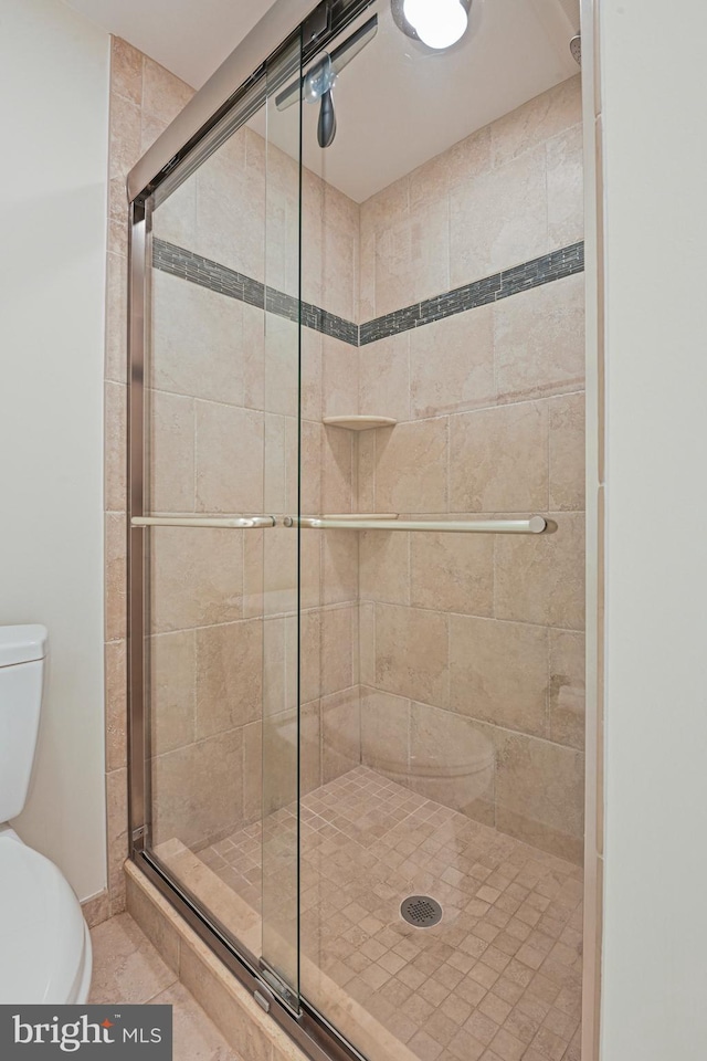 full bath with a stall shower, toilet, and tile patterned floors