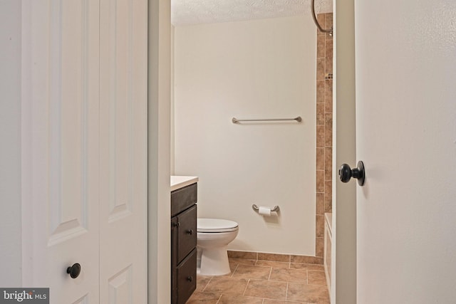 full bath featuring vanity, toilet, and a textured ceiling