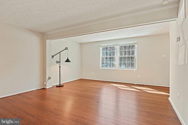 empty room with a textured ceiling, wood-type flooring, and baseboards