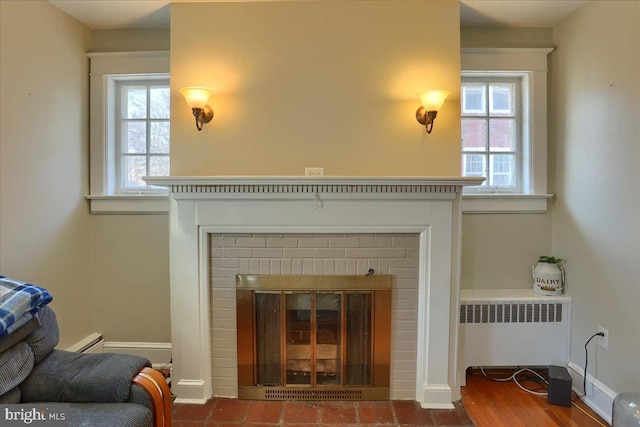 living room with a baseboard radiator, baseboards, radiator, and a fireplace