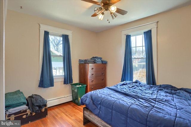 bedroom with a ceiling fan, wood finished floors, and a baseboard radiator