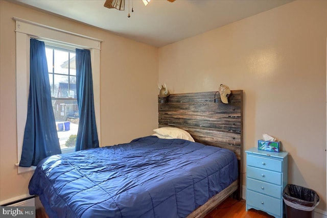 bedroom with wood finished floors and a baseboard radiator