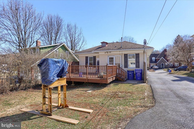 rear view of property featuring a shingled roof and a wooden deck