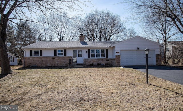 ranch-style house featuring a garage, driveway, stone siding, roof with shingles, and a chimney