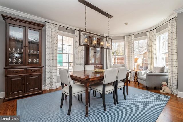 dining space with a notable chandelier, crown molding, baseboards, and dark wood-style flooring