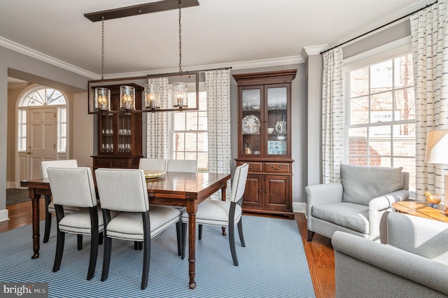 dining space with a notable chandelier, baseboards, dark wood finished floors, and crown molding