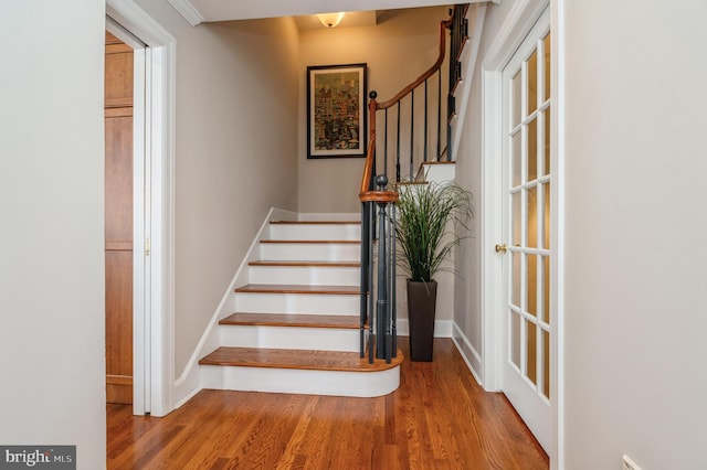 staircase featuring baseboards and wood finished floors