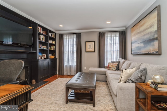 living area featuring a fireplace with flush hearth, ornamental molding, wood finished floors, and recessed lighting