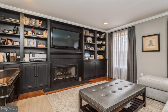 living area featuring ornamental molding, light wood-type flooring, and a fireplace with flush hearth