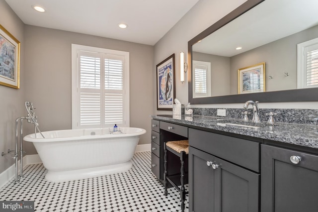 full bathroom featuring a soaking tub, recessed lighting, baseboards, and vanity