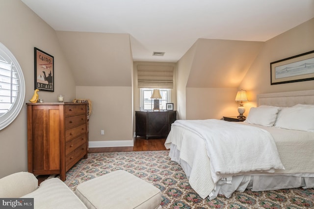 bedroom featuring vaulted ceiling, wood finished floors, visible vents, and baseboards