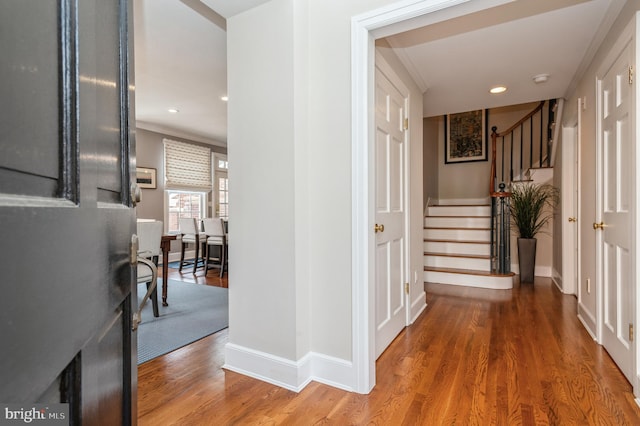 hallway featuring stairs, recessed lighting, wood finished floors, and baseboards