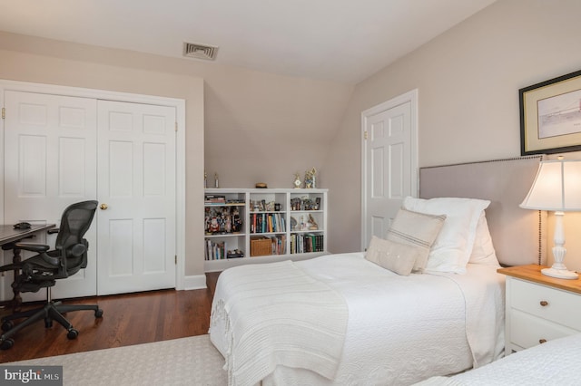 bedroom with a closet, visible vents, vaulted ceiling, and wood finished floors