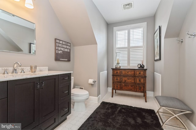 bathroom featuring toilet, vanity, visible vents, and baseboards