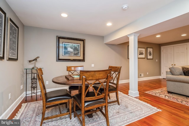 dining space featuring baseboards, ornate columns, wood finished floors, and recessed lighting