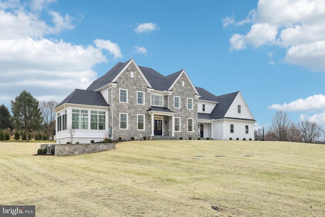 view of front facade featuring a standing seam roof, metal roof, a front lawn, and stone siding